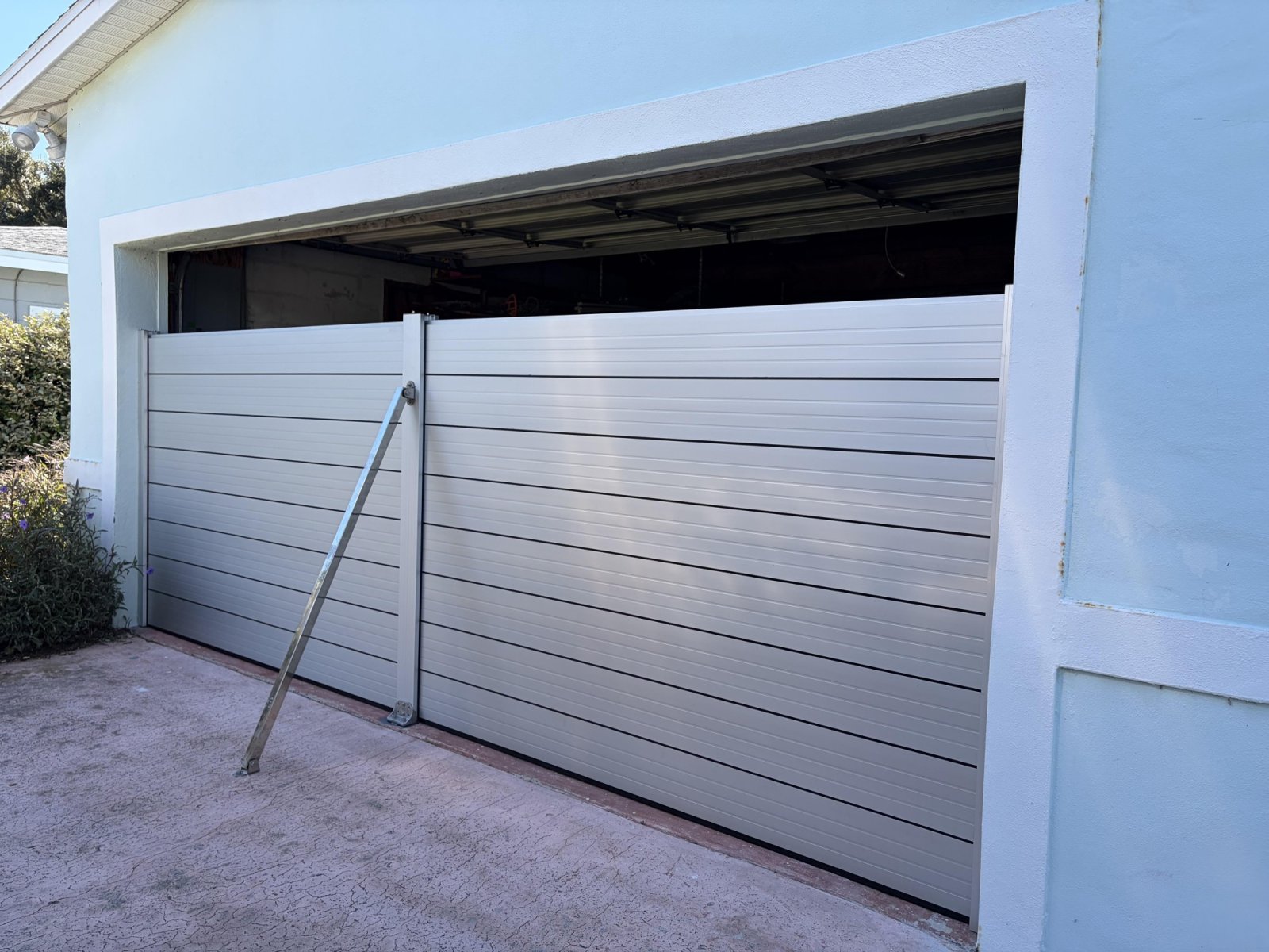 John’s St. Petersburg garage installation, showing aluminum panels, a middle column and an exterior brace, with the garage door partly raised. Installation photograph; not a flood-test result.